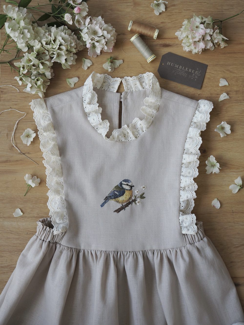 Graues Kleid mit Rüschen und gestickter Blaumeise