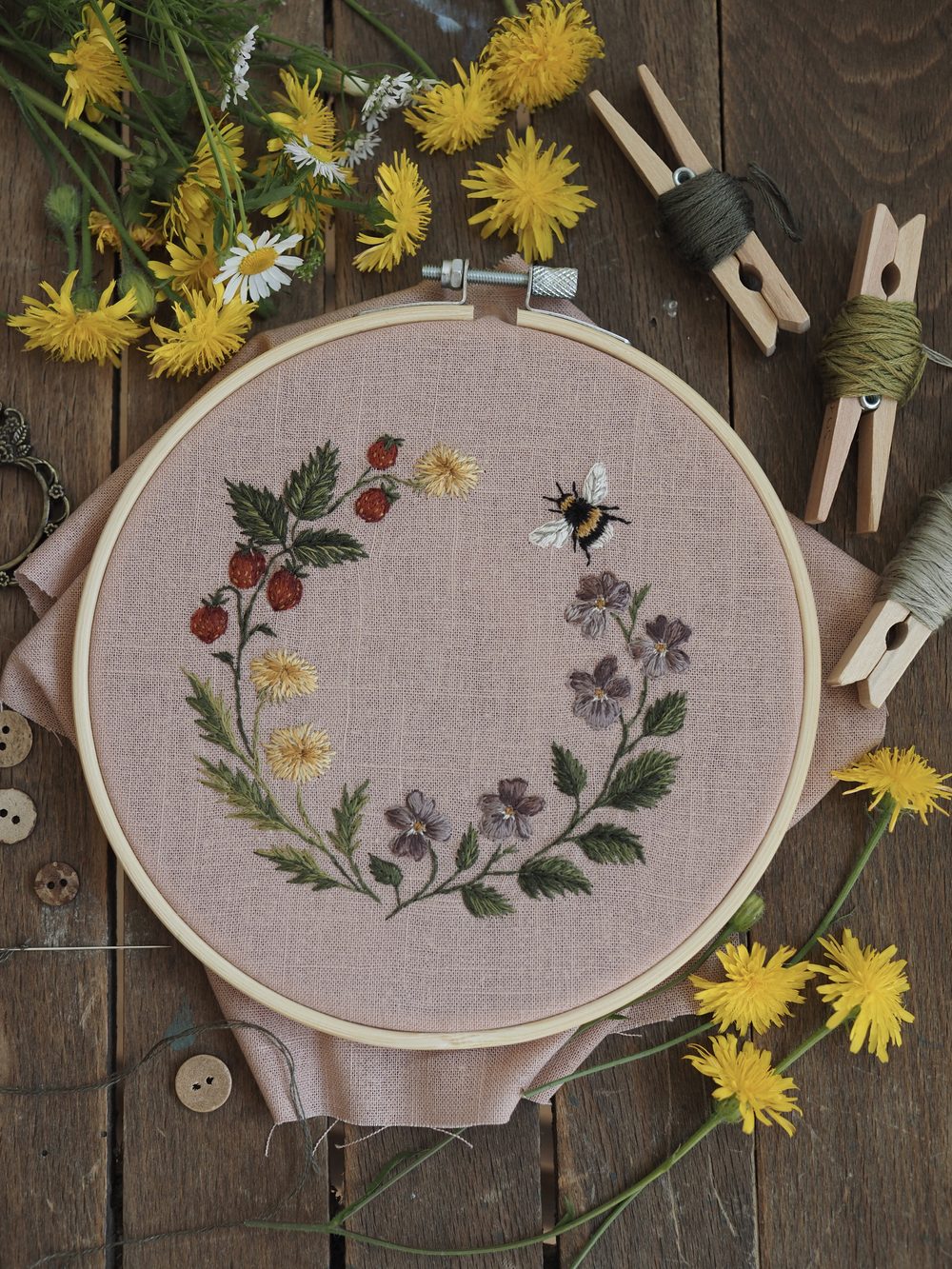 Gestickter Blütenkranz mit Hummel im Stickrahmen