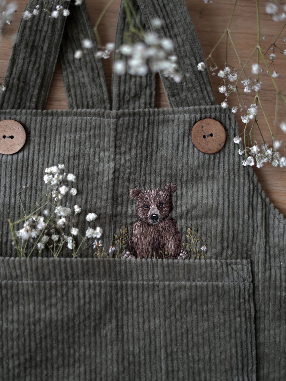 Olivgrüne Cordlatzhose mit gesticktem Bären in der Tasche