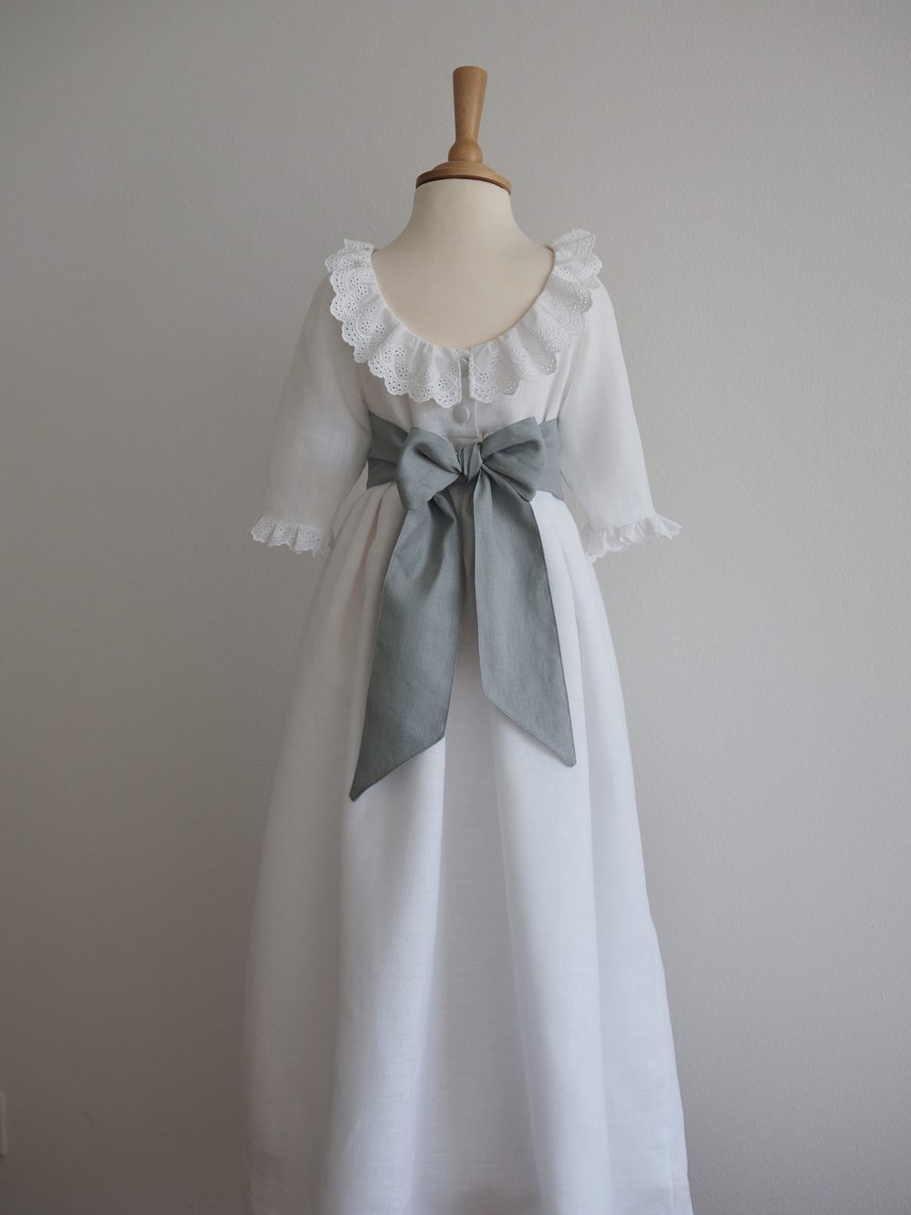 Weißes Festkleid mit Rüschenkragen und salbeigrüner Schleife