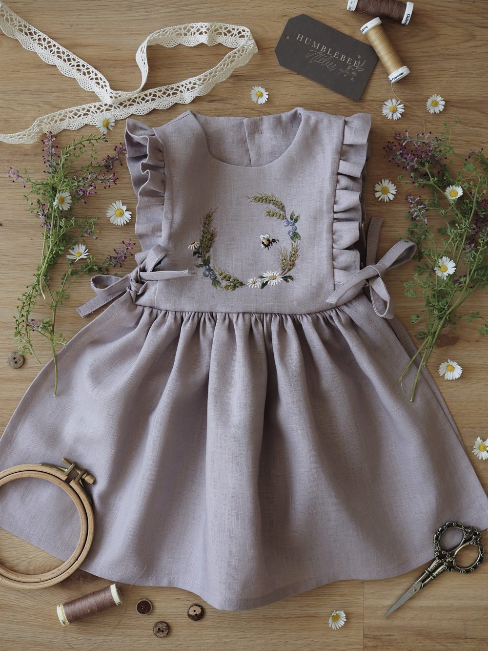 Fliederfarbenes Kleid mit gesticktem Kranz und Stickrahmen
