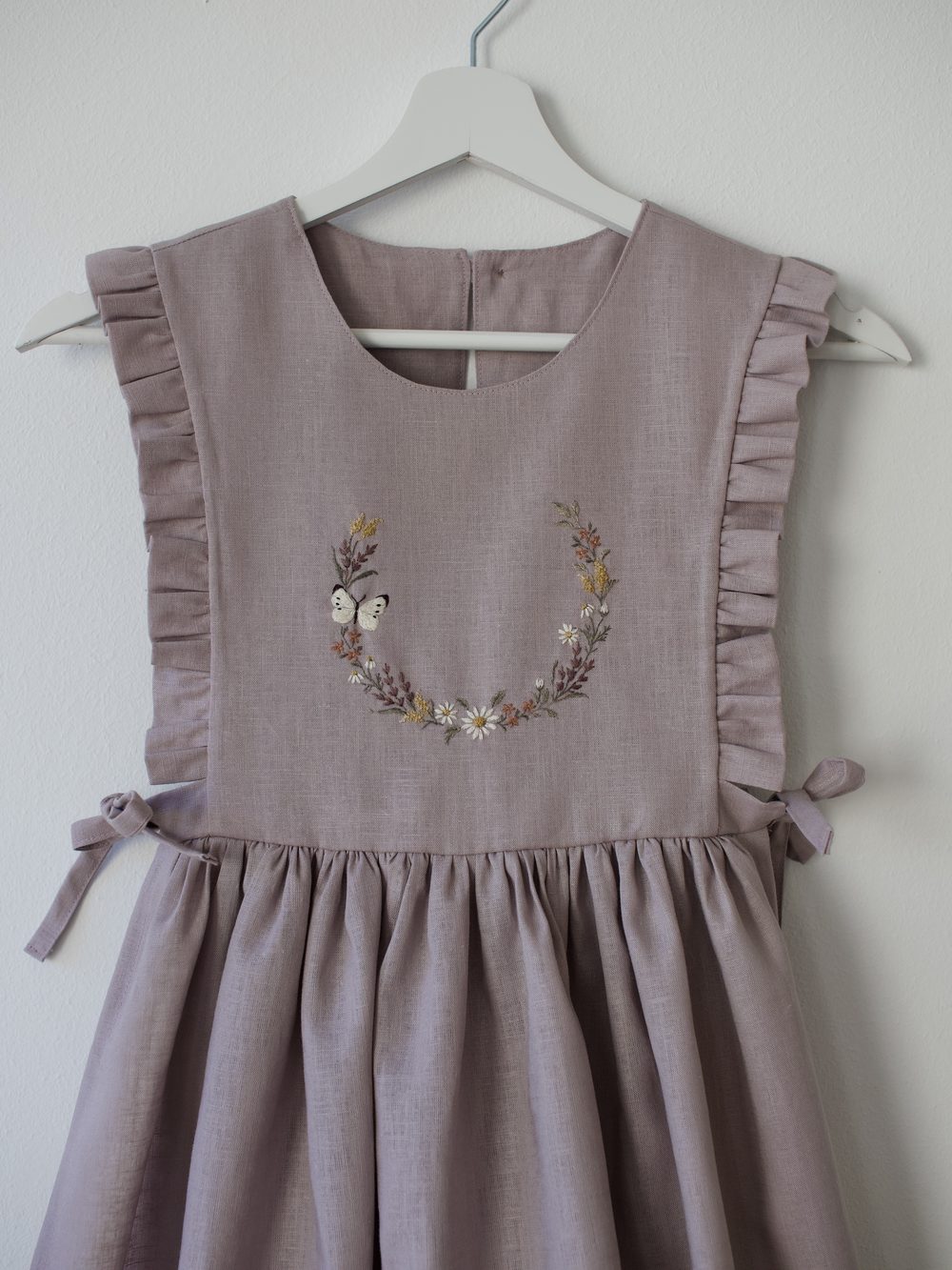 Fliederfarbenes Kleid mit gesticktem Blütenkranz und Schmetterling