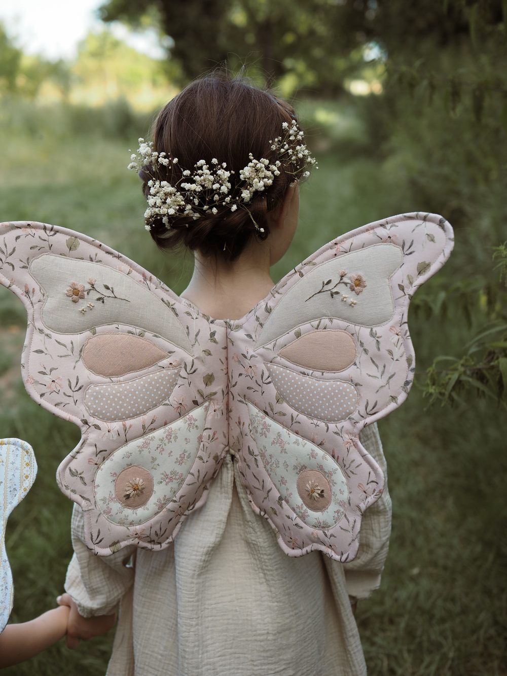 Mädchen mit Blumenkranz und rosa Schmetterlingsflügeln
