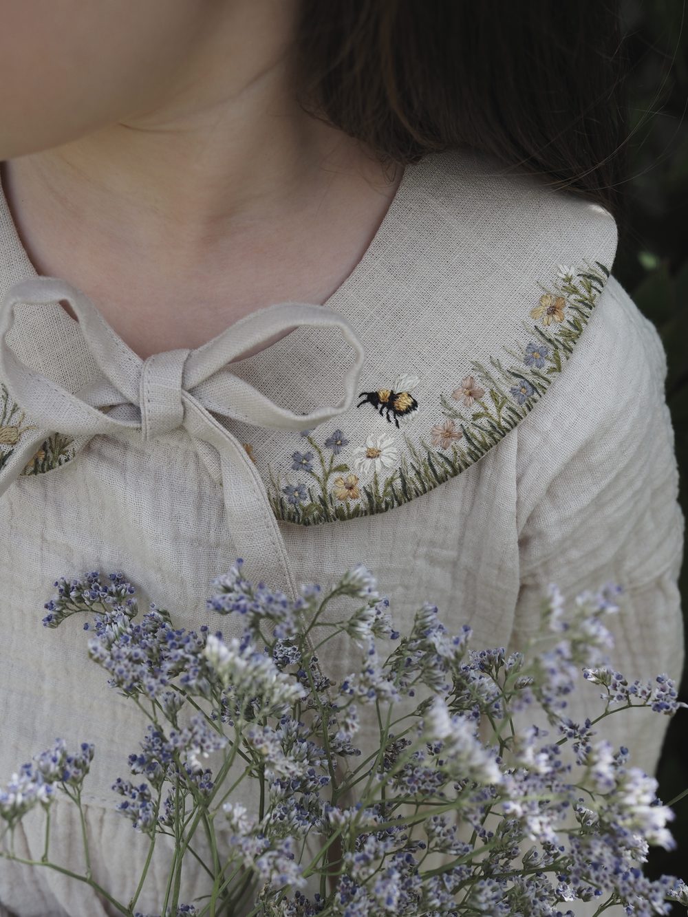 Getragener Leinenkragen mit Wiesenblumen und Hummel