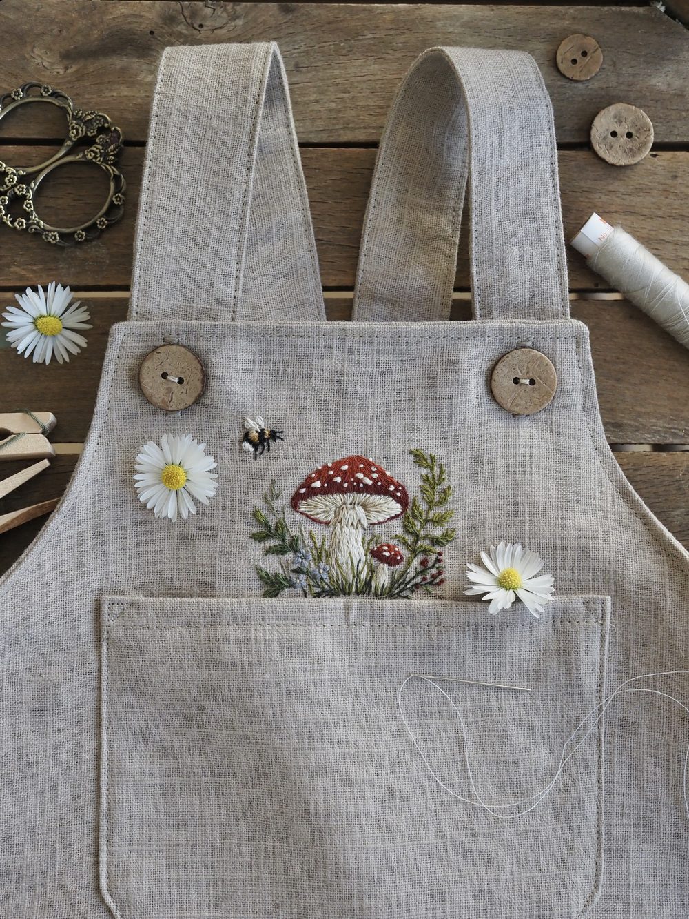 Bestickte Pilze und Blumen auf einer hellen Latzhose