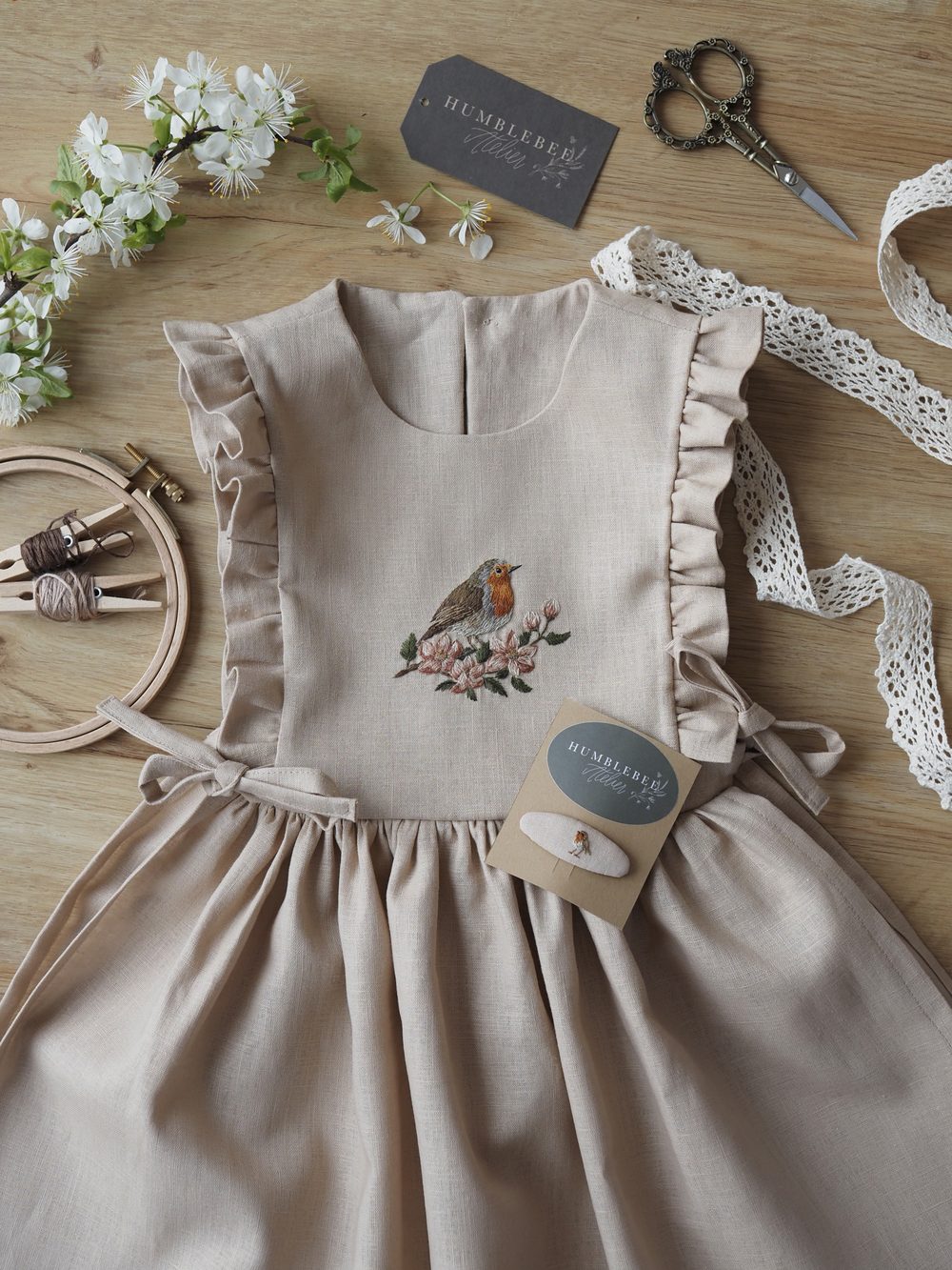 Helles Kleid mit Rüschen und gesticktem Rotkehlchen