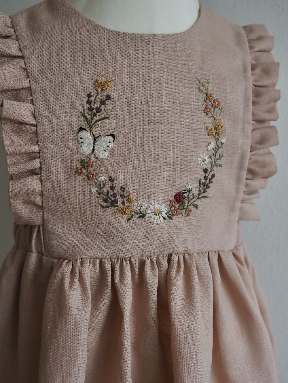 Altrosa Kleid mit gesticktem Blütenkranz und Schmetterling