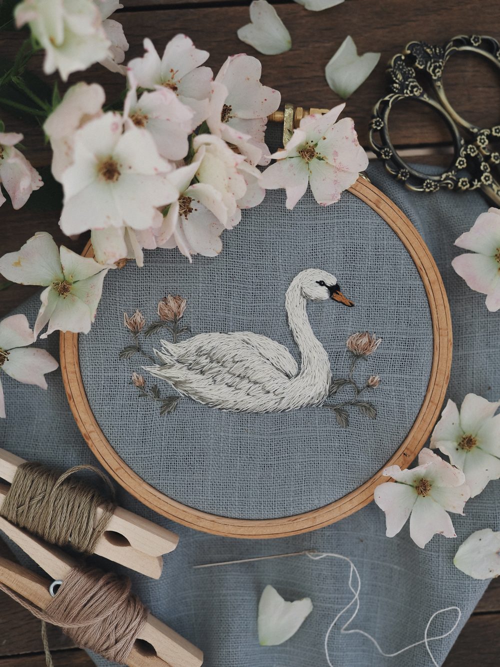 Gestickter Schwan auf blauem Leinen im Stickrahmen