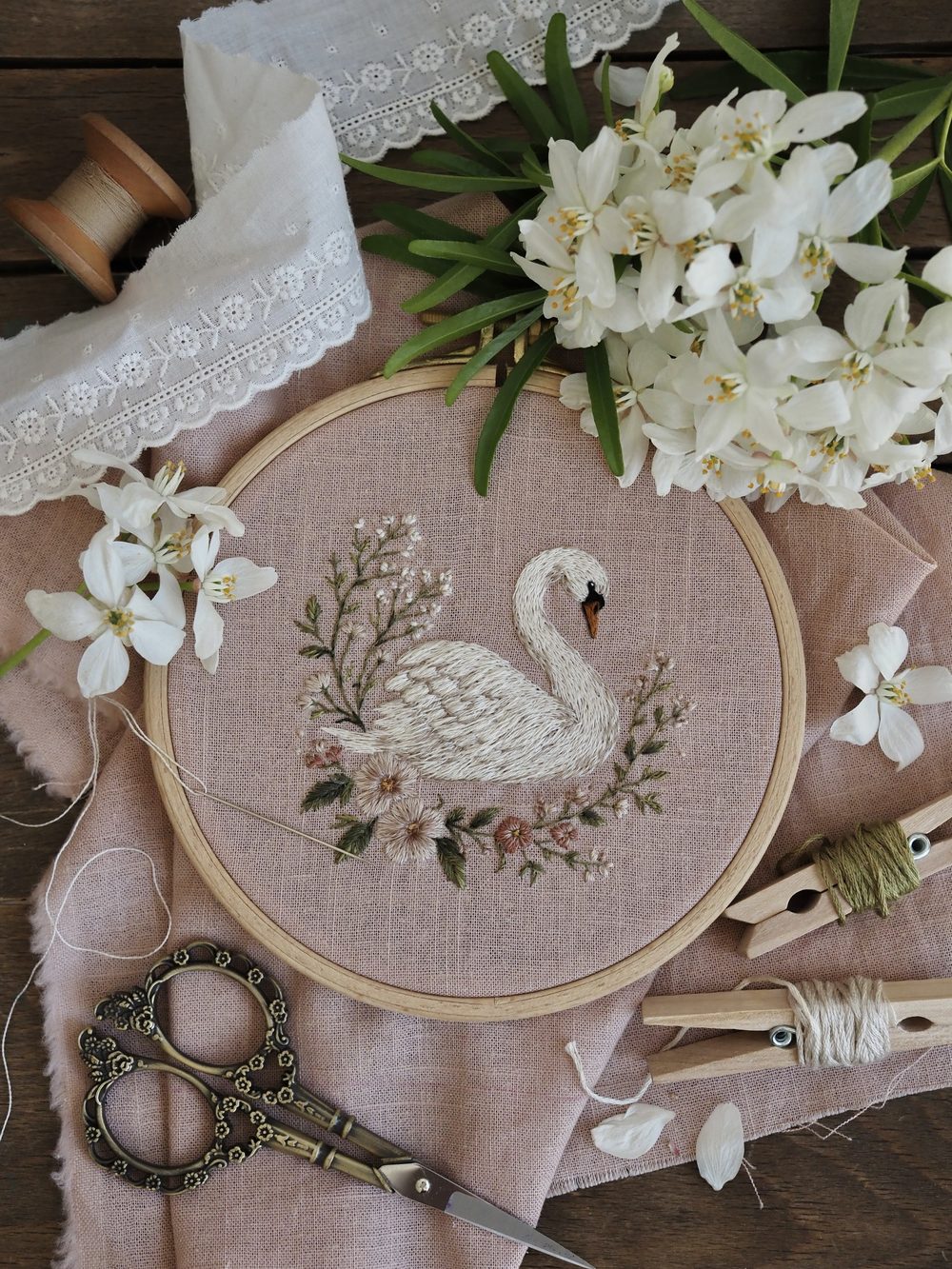Gestickter Schwan im Blütenkranz auf rosa Leinen