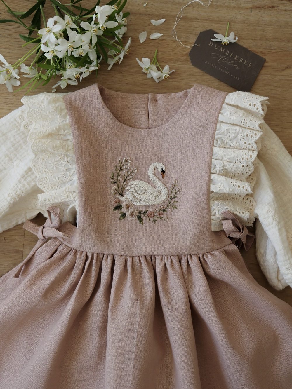 Rosa Kleid mit Spitzenärmeln und gesticktem Schwan