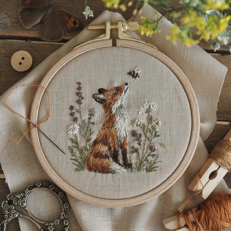 Handgestickter Fuchs zwischen Gräsern im Stickrahmen
