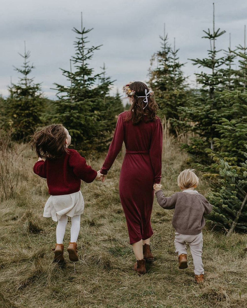 Alina mit ihren beiden Kindern an der Hand auf einem Weg zwischen jungen Tannen