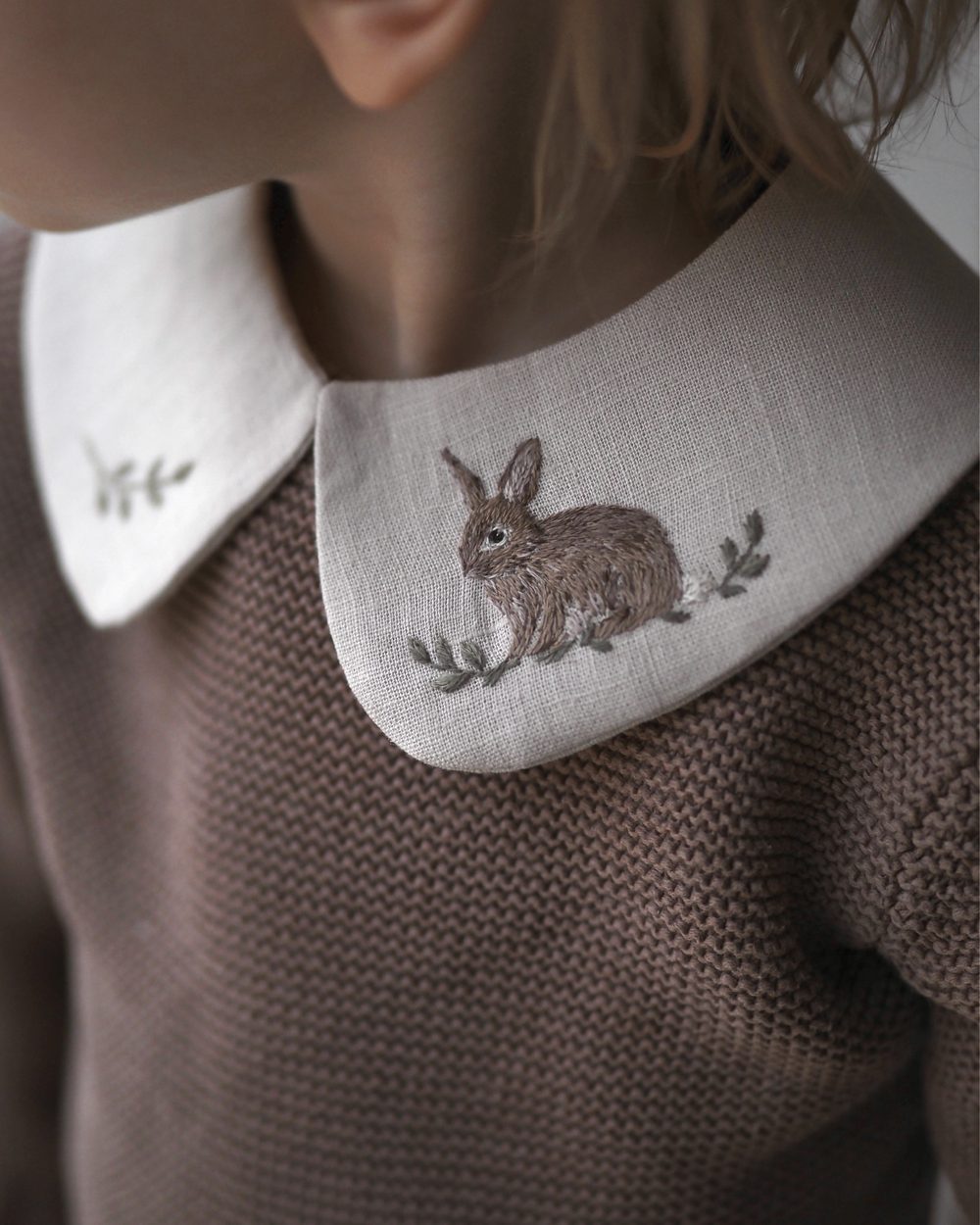 Bestickter Kragen mit Hase auf einem braunen Pullover